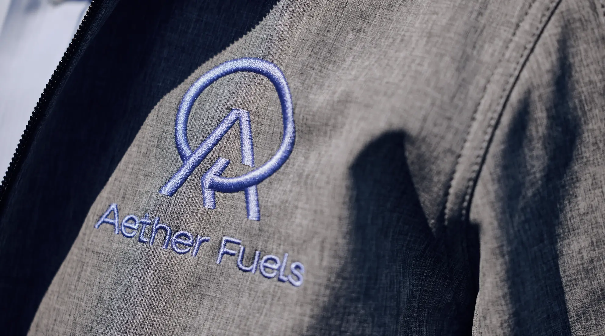 The Aether Fuels logo embroidered onto the breast of a suit coat